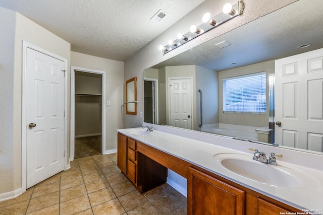 bathroom featuring a textured ceiling, tile patterned floors, a bath, and vanity