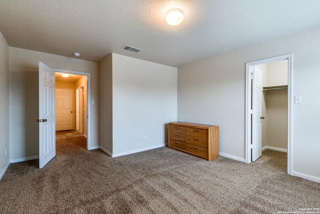 unfurnished bedroom featuring a spacious closet, a closet, and dark carpet