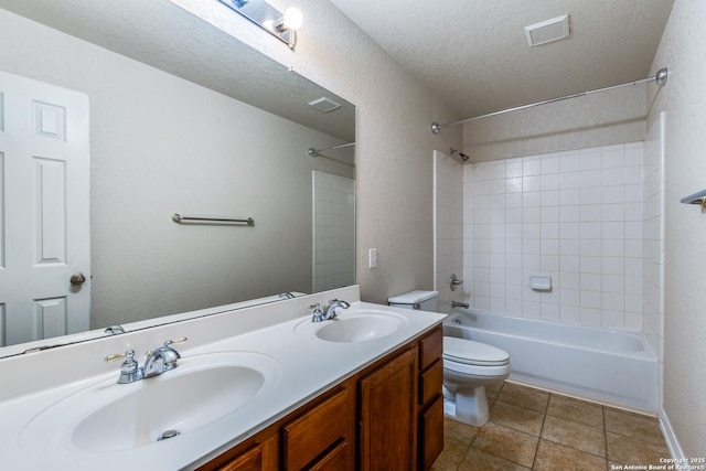 full bathroom with a textured ceiling, tiled shower / bath, tile patterned flooring, vanity, and toilet