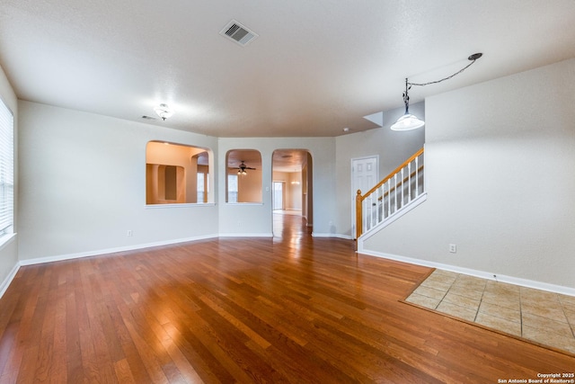 unfurnished living room featuring ceiling fan, a wealth of natural light, and hardwood / wood-style flooring