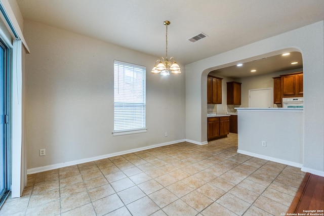 kitchen featuring light tile patterned floors, white oven, an inviting chandelier, and pendant lighting