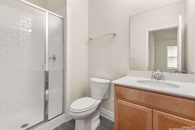 bathroom featuring a shower with shower door, toilet, and vanity