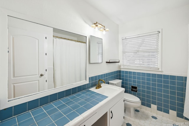 bathroom with tile patterned flooring, vanity, tile walls, and toilet