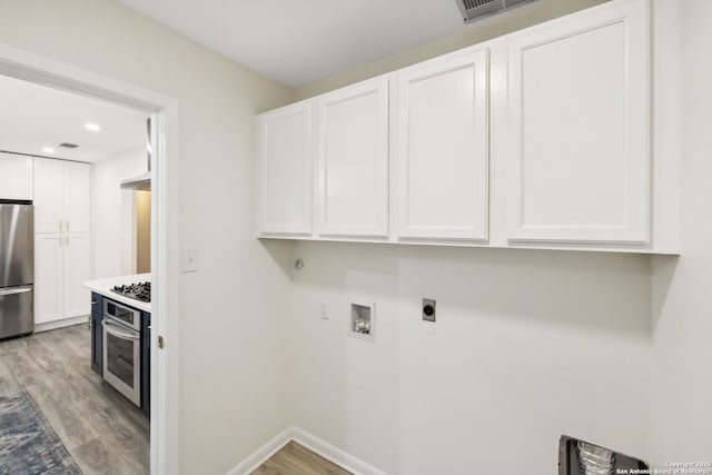 washroom with cabinets, electric dryer hookup, washer hookup, and light hardwood / wood-style flooring