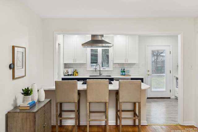 kitchen featuring white cabinetry, sink, exhaust hood, and a kitchen bar