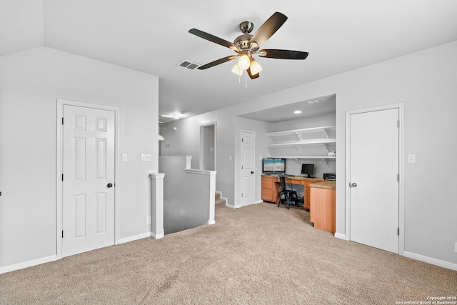 interior space with ceiling fan, light colored carpet, visible vents, baseboards, and built in study area