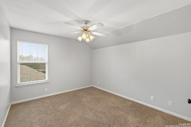 carpeted spare room featuring a ceiling fan, lofted ceiling, and baseboards