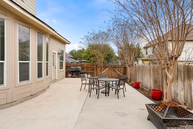 view of patio featuring a fire pit, outdoor dining space, a fenced backyard, and a grill