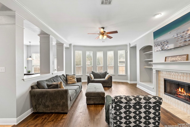 living area with dark wood-style floors, plenty of natural light, a fireplace, and crown molding