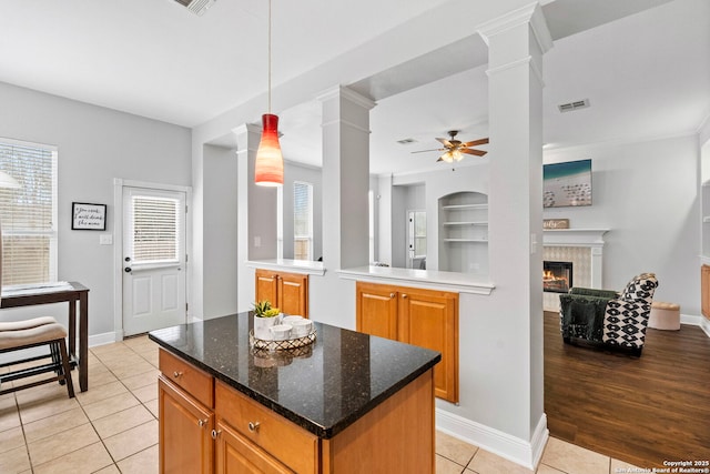 kitchen featuring hanging light fixtures, decorative columns, visible vents, and brown cabinets