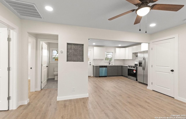 kitchen featuring white cabinetry, stainless steel appliances, tasteful backsplash, light hardwood / wood-style flooring, and sink