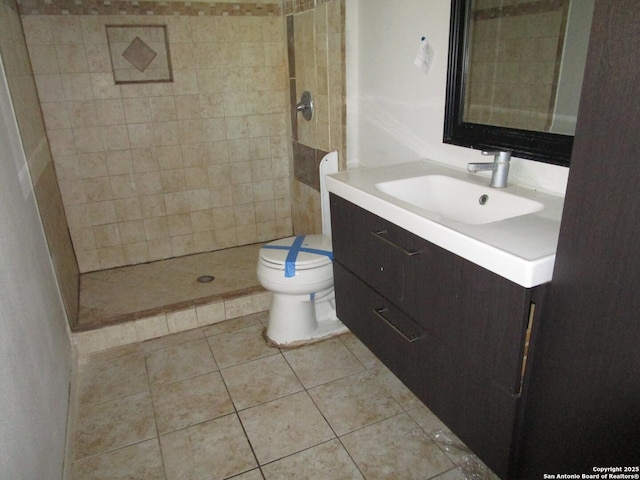 bathroom with toilet, vanity, tile patterned floors, and a tile shower