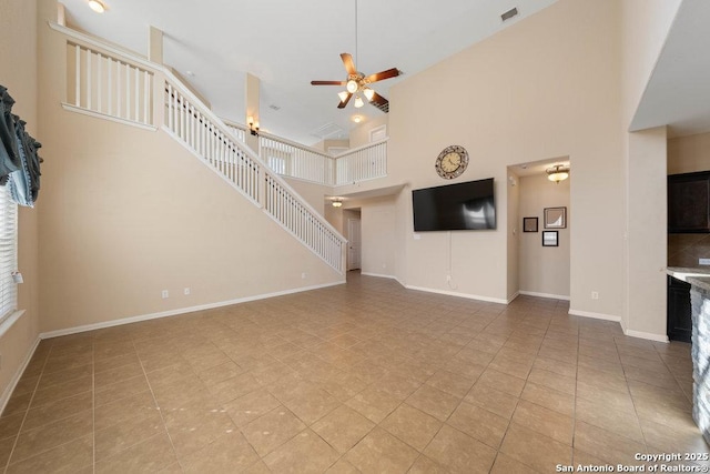 unfurnished living room with ceiling fan, a high ceiling, and light tile patterned floors