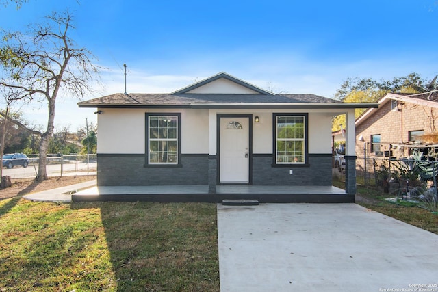 bungalow-style home featuring covered porch, stucco siding, a front lawn, and fence