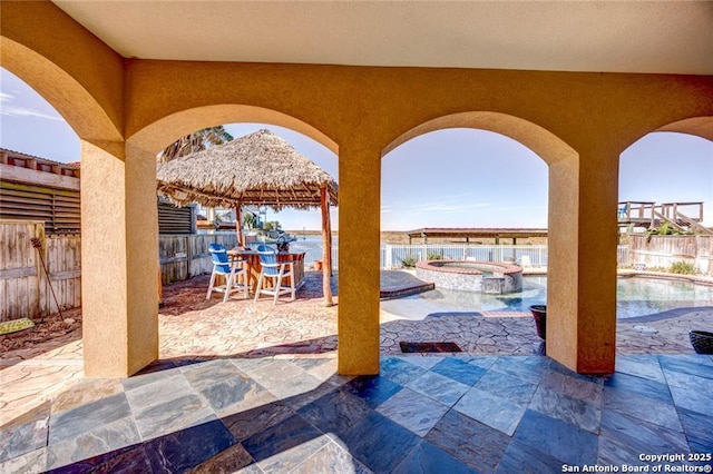 view of patio featuring a pool with hot tub, a gazebo, and a water view