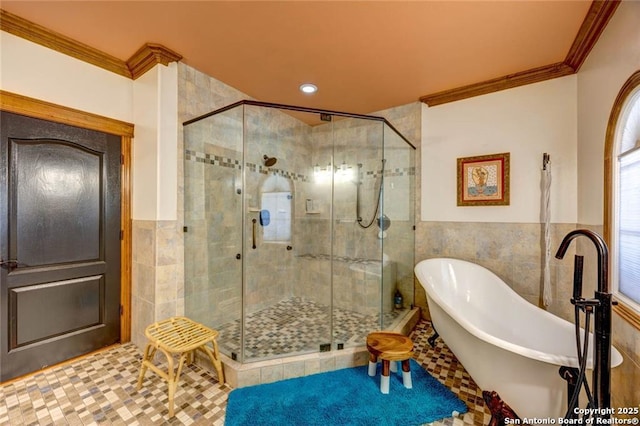 bathroom with a stall shower, a freestanding tub, tile walls, and crown molding