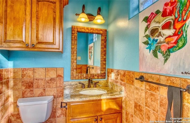 bathroom with tile walls, toilet, and vanity