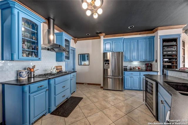 kitchen featuring wine cooler, stainless steel appliances, wall chimney range hood, blue cabinetry, and dark countertops