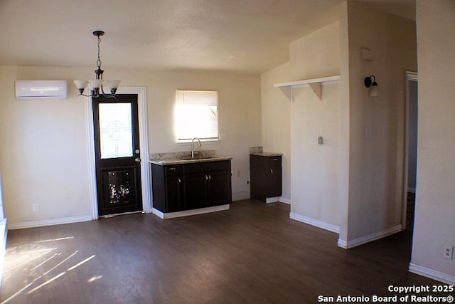 kitchen with dark hardwood / wood-style floors, a notable chandelier, a wall unit AC, sink, and hanging light fixtures