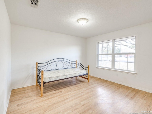 bedroom featuring light wood-type flooring and a textured ceiling