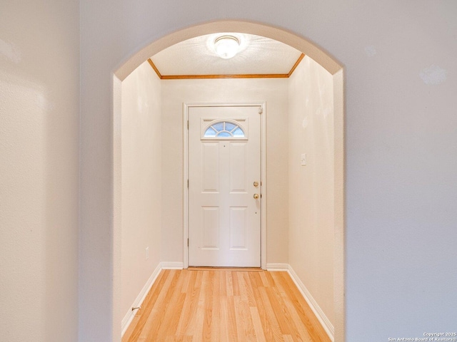 doorway to outside with ornamental molding and wood-type flooring