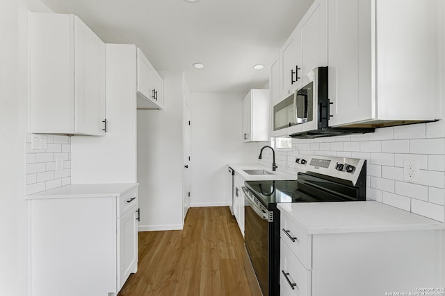 kitchen with tasteful backsplash, sink, white cabinetry, light hardwood / wood-style flooring, and stainless steel appliances