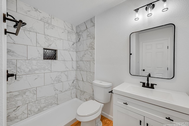 bathroom featuring toilet, vanity, and tiled shower