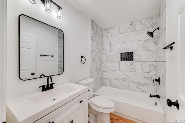 full bathroom featuring toilet, tiled shower / bath, and vanity