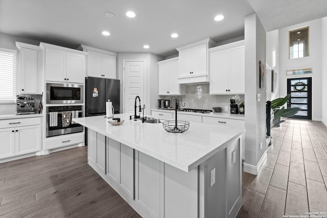 kitchen with black refrigerator, a center island with sink, oven, and built in microwave