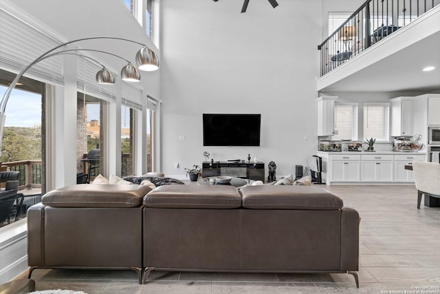 living room featuring ceiling fan, a healthy amount of sunlight, and a high ceiling