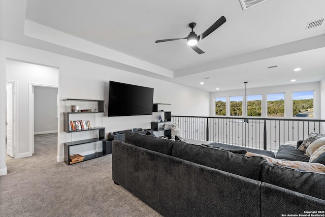 living room featuring ceiling fan, a raised ceiling, and light carpet