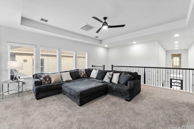 carpeted living room featuring ceiling fan, a wealth of natural light, and a tray ceiling