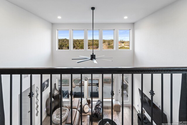 staircase with ceiling fan, a wealth of natural light, and hardwood / wood-style floors