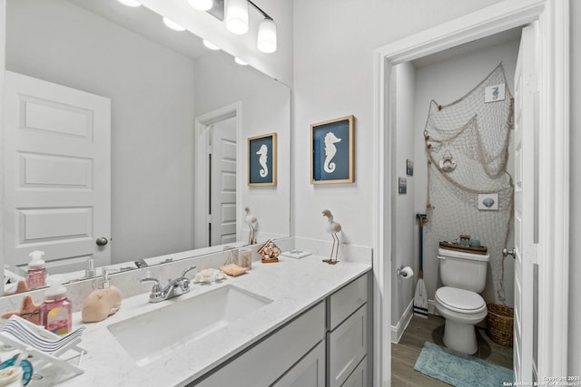 bathroom featuring wood-type flooring, toilet, and vanity