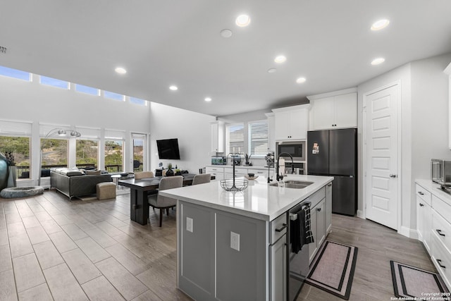 kitchen featuring white cabinets, black appliances, sink, a kitchen breakfast bar, and a kitchen island with sink