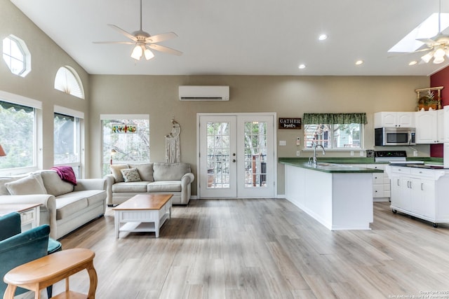 kitchen with light wood-type flooring, french doors, white cabinets, an AC wall unit, and sink