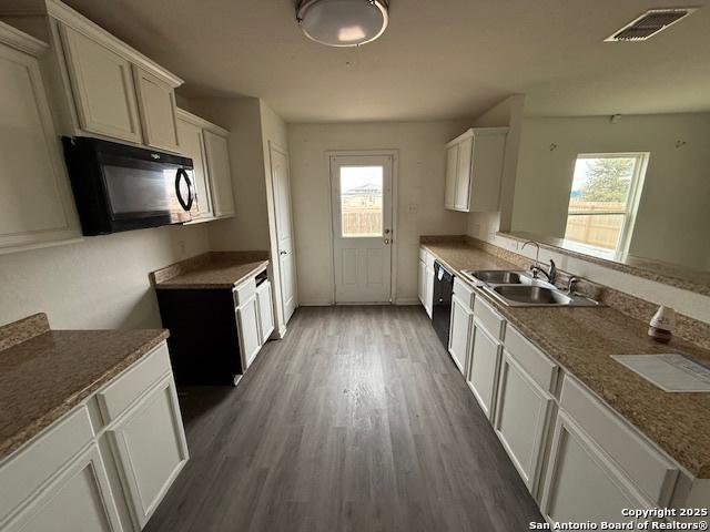 kitchen with black appliances, plenty of natural light, sink, and white cabinetry