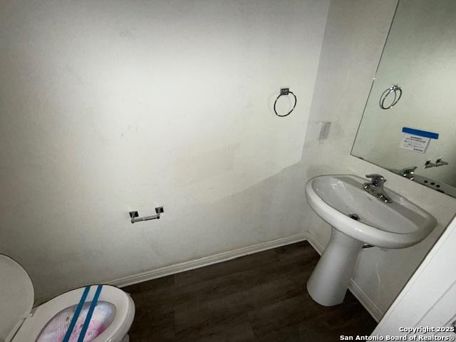 bathroom with toilet, wood-type flooring, and sink