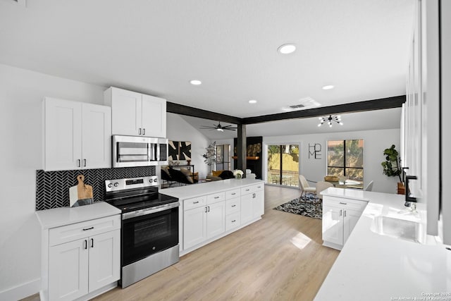 kitchen with kitchen peninsula, decorative backsplash, white cabinetry, light hardwood / wood-style flooring, and stainless steel appliances