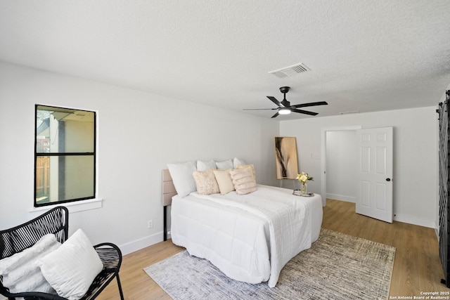 bedroom featuring ceiling fan, a textured ceiling, and light hardwood / wood-style flooring