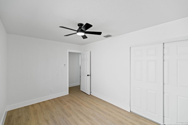 unfurnished bedroom with light wood-type flooring, ceiling fan, and a closet