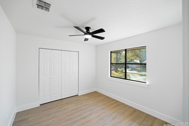 unfurnished bedroom with ceiling fan, light wood-type flooring, and a closet