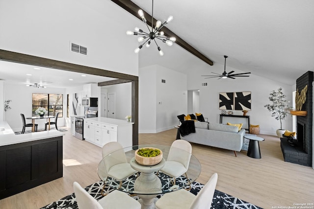 dining space featuring light wood-type flooring, lofted ceiling with beams, a fireplace, and ceiling fan with notable chandelier