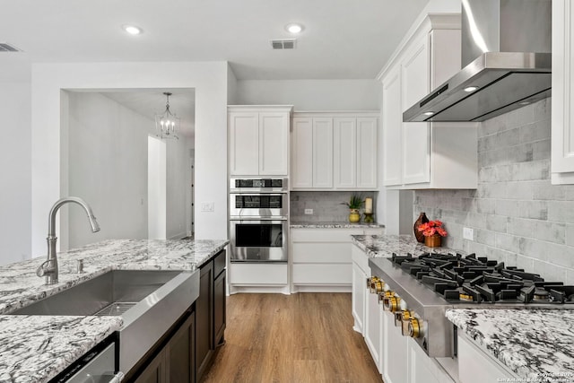 kitchen with sink, white cabinetry, wall chimney exhaust hood, and stainless steel appliances