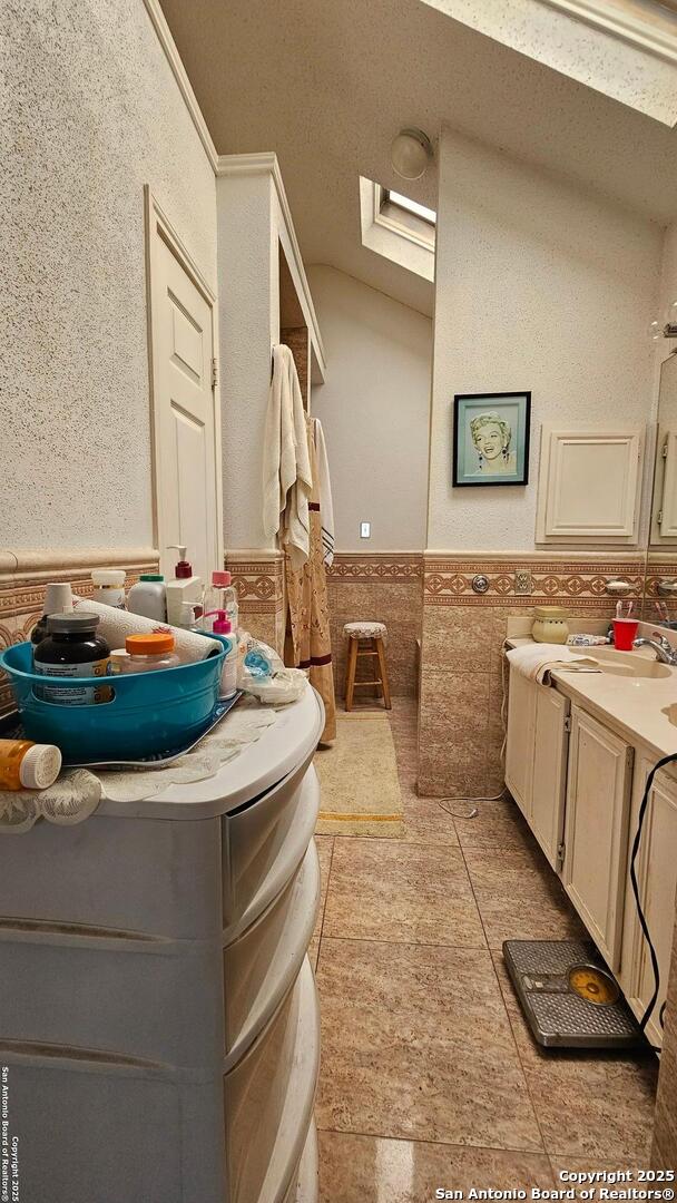 bathroom featuring vanity, wainscoting, and tile walls