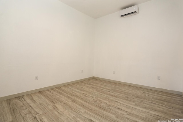 spare room with an AC wall unit and light hardwood / wood-style floors