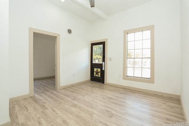 spare room featuring light hardwood / wood-style flooring and beam ceiling