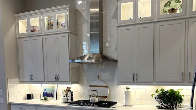 kitchen with stainless steel gas stovetop, white cabinetry, decorative backsplash, and wall chimney range hood