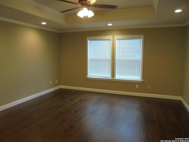 empty room featuring dark hardwood / wood-style flooring, ornamental molding, ceiling fan, and a tray ceiling