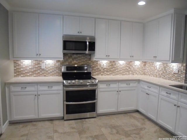 kitchen featuring tasteful backsplash, white cabinetry, and stainless steel appliances